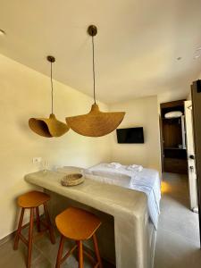 Habitación con 1 cama con 2 sillas y 2 luces colgantes en Serenity Suites, en Halki
