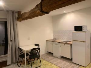 eine kleine Küche mit einem Tisch und einem weißen Kühlschrank in der Unterkunft Grange Rousselin in Bachivillers