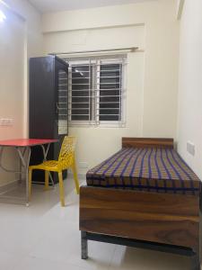 a bedroom with a bed and a table and a chair at SSV stays in Bangalore