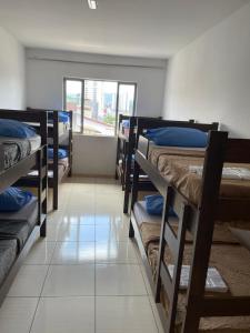 Cette chambre est dotée de carrelage et de plusieurs lits superposés. dans l'établissement Hostel Salus, à Barueri