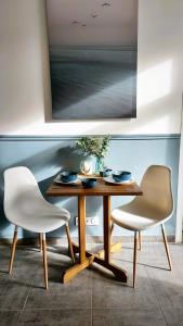 uma mesa de jantar e duas cadeiras brancas num quarto em L'appartement de l'Arche em Châteauneuf-de-Gadagne