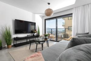 a living room with a couch and a tv and a table at סוויטה מרווחת, רומנטית ומפנקת in Eilat