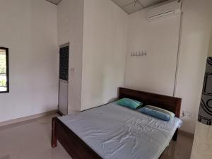 a bed in a white room with two blue pillows at Sunfa Resort in Ambalantota