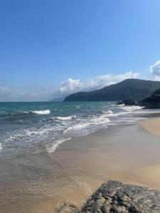 a beach with the ocean and some rocks in the sand at Linda Casa em uma linda praia - Santiago/ Maresias in São Sebastião