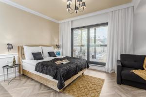um quarto com uma cama, uma cadeira e uma janela em Deo Apartamenty na Wyspie Spichrzów em Gdansk