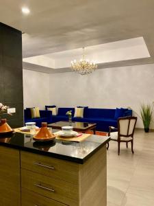 a kitchen and living room with a blue couch at Apt Raffiné Taghazout Bay Vue Océan luxe 6p in Tamraght Ouzdar