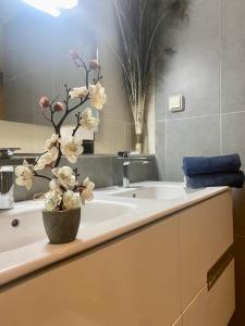 a bathroom sink with a vase with flowers on it at Apt Raffiné Taghazout Bay Vue Océan luxe 6p in Tamraght Ouzdar