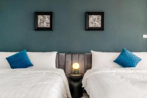 a bedroom with two beds with blue and white pillows at H& Sunset Mu Style Inn in Xiaoliuqiu