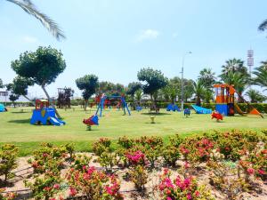 park ze sprzętem do zabaw i kwiatami w obiekcie Casa de Playa Deluxe en Condominio Playa Coral w mieście Fundo Copacabana