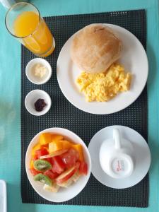 uma mesa com dois pratos de comida para o pequeno-almoço e um copo de sumo de laranja em HOSTAL TERO REAL em Puerto Villamil