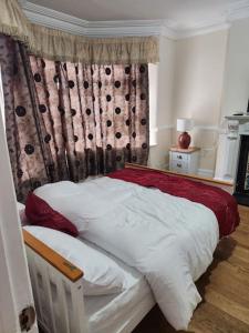um quarto com uma cama branca com lençóis vermelhos e brancos em Comfy Guest House em Londres