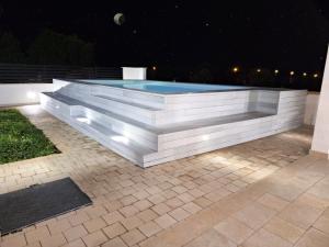 uma piscina com um banco à volta à noite em B&B Villa Noemi em Porto Cesareo