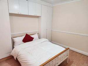 a small bedroom with a bed with a red pillow at Comfy Guest House in London