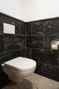 a bathroom with a toilet and a black tiled wall at Apartments Edinger in Söll