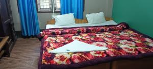 a bedroom with a bed with a red floral blanket at Aajanta in Tawang
