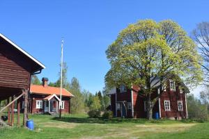 Una casa vieja con un árbol delante. en Charming renovated seventeenth century cottage, en Ludvika