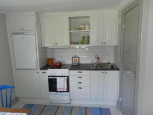 una cocina con armarios blancos y fregadero en Charming renovated seventeenth century cottage, en Ludvika