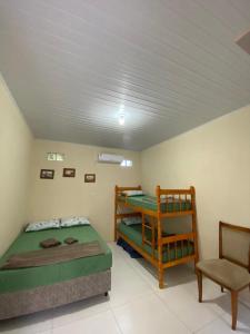 sypialnia z 2 łóżkami piętrowymi i krzesłem w obiekcie Pousada Ferreira w mieście São Gabriel