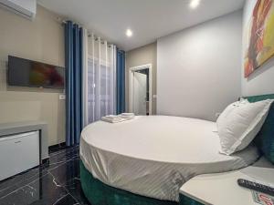 un grande letto bianco in una camera con TV di Rumani 3 Islands Hotel a Ksamil