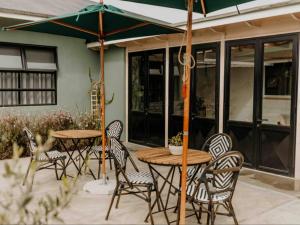 eine Terrasse mit 2 Tischen, Stühlen und einem Sonnenschirm in der Unterkunft Fancy Fritz B&B in Swakopmund