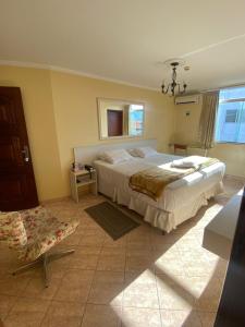 a bedroom with a large bed and a chair at Pousada Emaús in Cruzeiro