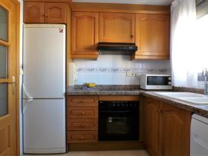 a kitchen with wooden cabinets and a white refrigerator at Apartamento turístico en Gemelos 20, planta 14 in Benidorm