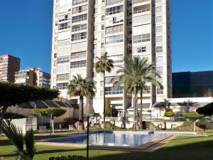 a large white building with palm trees in front of it at Apartamento turístico en Gemelos 20, planta 14 in Benidorm