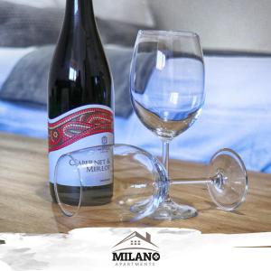 una botella de vino y una copa en una mesa en Milano Apartman ****, en Brzeće