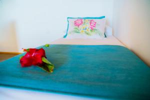 Matariki Sunset Apart Hotel في هانجا روا: سرير عليه وردة حمراء ومخدة