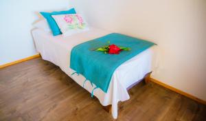 a bed with a blue blanket and flowers on it at Matariki Sunset Apart Hotel in Hanga Roa