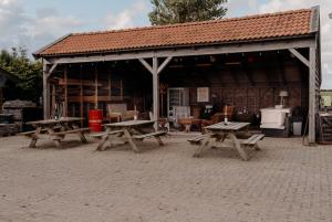 einem Pavillon mit Picknicktischen vor einem Gebäude in der Unterkunft Finse Woning op Camping De Tulpenweide in Breezand