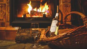 a bottle of wine and a glass in front of a fireplace at Winnica Nad Źródłem - Domki w winnicy in Sierzawy