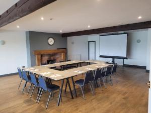 a conference room with a large table and chairs and a screen at The White Horse Lodge Hotel in Thirsk