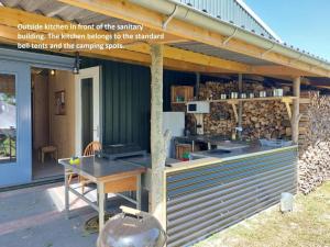 a building with a deck with a table in front of it at Bell tent Glamping Essenhof in Aagtekerke +3 photos