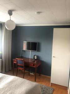 una camera da letto con scrivania e TV su una parete blu di Vrigstad Rumshotell a Vrigstad