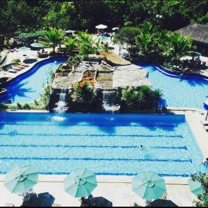 a large swimming pool with a water park with umbrellas at Ecologic Ville Resort Apto há 900 mt do centro de Caldas Novas in Caldas Novas