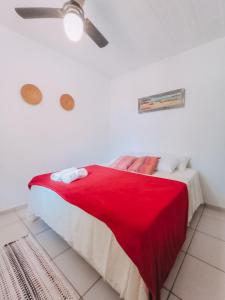 een slaapkamer met een rood bed en een plafondventilator bij Buzios Praia Caravelas cs 11 in Baía Formosa