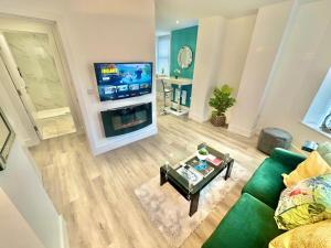 a living room with a green couch and a tv at Coastal Vibes - Stunning Bournemouth Apartment with King Size Bed and Free Parking - Central Location and Close to Beach in Bournemouth