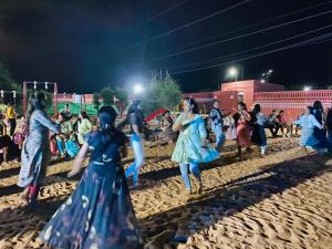 um grupo de pessoas dançando na areia à noite em Santkrupa Villa Resort em Nakhtrana
