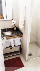 a bathroom with a sink and a mirror and a shower at Apto Praia da Enseada 4 pessoas in Guarujá