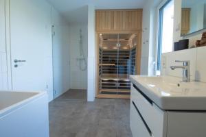 une cuisine blanche avec un évier et une cave à vin dans l'établissement Sielhuus 11 Ferienwohnung mit Dachterrasse und Infrarotsauna und Kamin für bis zu 4 Personen in Fedderwardersiel!, à Fedderwardersiel