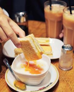 a person holding a piece of bread in a bowl of soup at Caravel Hotel in Macau