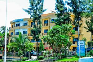 un bâtiment jaune avec des arbres devant lui dans l'établissement Hill View Hotel Kiyovu, à Kigali