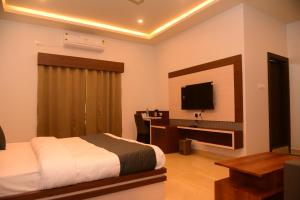 a bedroom with a bed and a flat screen tv at Hotel Larmika in Hatikhuli