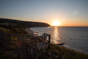 a sunset over the ocean with a wooden fence at Host & Stay - Old Harry Rocks in Swanage