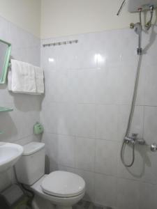 a white bathroom with a toilet and a shower at Nhà Nghỉ Du Lịch Nguyên Vũ in Da Lat +17 photos
