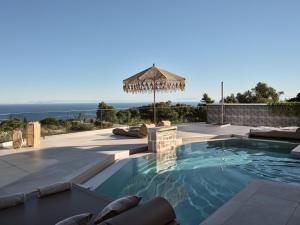 a swimming pool with an umbrella and the ocean at Ocean Luxury Villas in Volimes