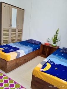 a bedroom with two beds and a night stand at WismaALAS Syariah Guesthouse in Sintang