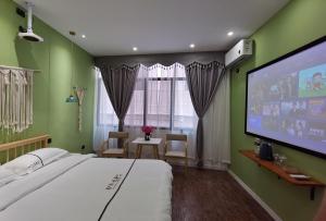 Schlafzimmer mit einem Bett und einem Flachbild-TV in der Unterkunft Enshi Miaoer One Residence in Enshi