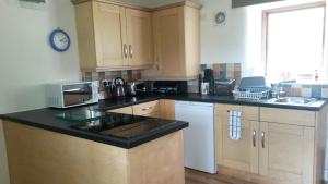a kitchen with wooden cabinets and a black counter top at Gibraltar Farm Cottage in Hebden Bridge